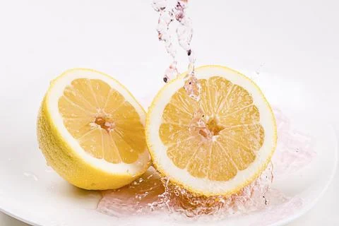 Red tinted water splashes onto lemons. Stock Photos
