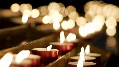 Red tiny candles waving in a dark background in a church. Slow motion. Stock Footage 101898427