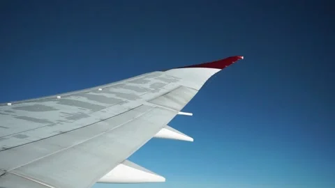 Red-tipped wing of plane during flight against blue sky Stock Footage 235650396