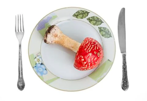 Red toadstool on dish with knife and fork. Stock Photos