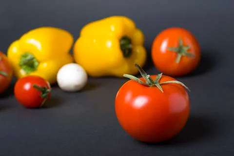 Red tomato on a background of different vegetables. Stock Photos