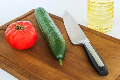 Red tomato, green cucumber and chef kitchen knife on a cutting board Stock Photos