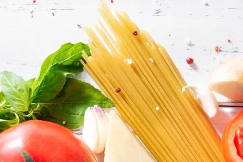 Red tomato,  raw spaghetti paste, spices, green Basil,  piece of cheese, garl Stock Photos