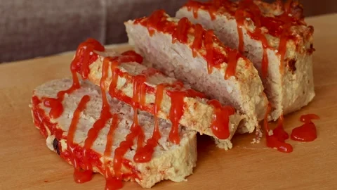 Red tomato sauce pouring on beef meatloaf slices on wooden cutting board Stock Footage 280857722