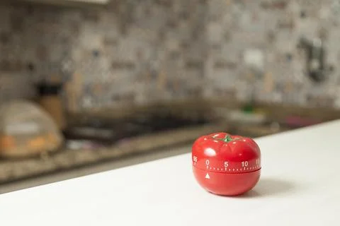 Red tomato-shaped kitchen timer with cooking in the background. To let you kn Foto stock