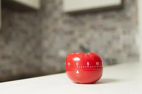 Red tomato-shaped kitchen timer with cooking in the background. To let you kn Photos