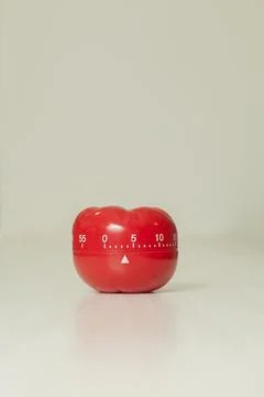 Red tomato-shaped kitchen timer with cooking in the background. To let you kn Stock Photos