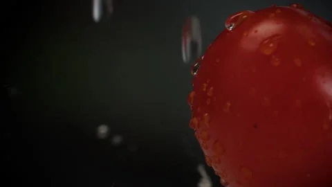Red tomatoes are lying on the board with water dripping on them slow motion Stock Footage 204717337