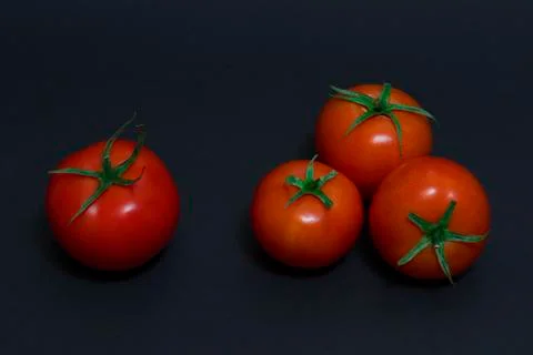 Red tomatoes on a dark background. Four red tomatoes on a dark background. Stock Photos