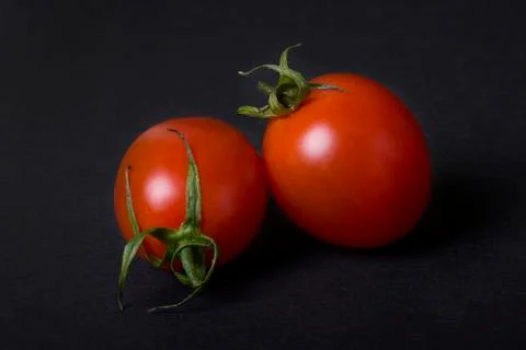 Red tomatoes on a dark background.Two red tomatoes on a dark background. Foto stock