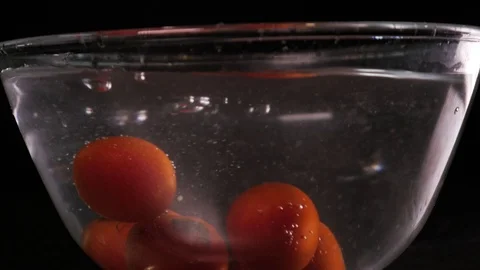 Red tomatoes fall and float in water, black background 库存影片 108685632