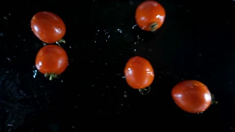 Red tomatoes fall on black in slow motion. Stock Footage 140191757