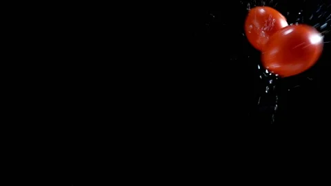 Red tomatoes fall in slow motion on a wet black surface Stock Footage 133222517