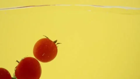 Red tomatoes falling into a water isolated on yellow background Stock-Footage 153479622