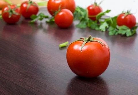 Red tomatoes  on a table on the background of vegetables. Stock Photos