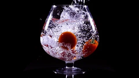 Red tomatoes with water dropping into the big wineglass in extreme slow motion 動画素材 77761179