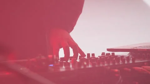Red tones highlighting a DJ's hand on mixing equipment at a live event Stock Footage 301693104