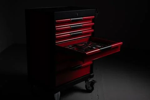 Red tool cabinet with open drawer in dark workshop Stock Photos