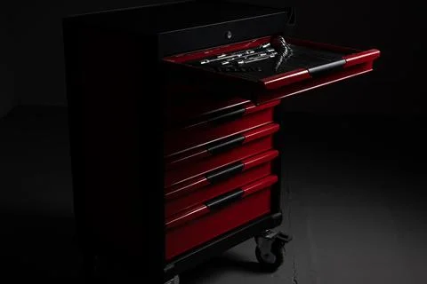 Red tool chest with open drawer and organized tools in dark workshop Stock Photos