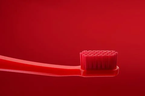 Red toothbrush without paste on a red background. Oral hygiene of the mouth. Stock Photos