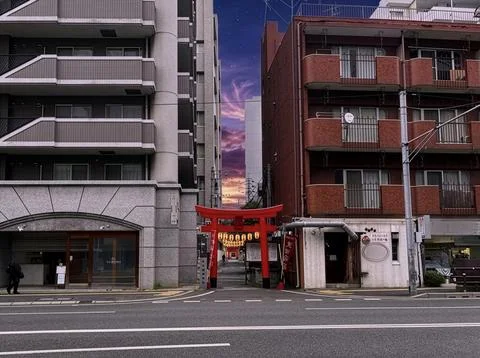 Red Torii Gate Between City Buildings with Japanese Lanterns and Moody Sky Stock Photos