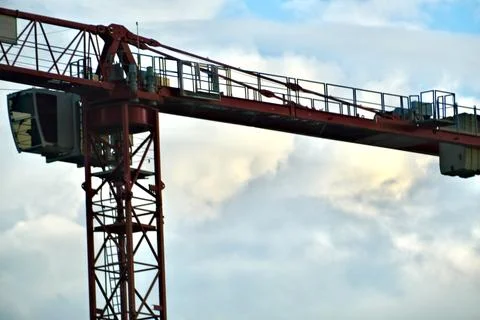 Red tower crane structure with mast and machinery against cloudy sky 库存照片