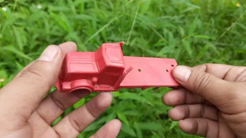 Red Toy Truck Held in Hands Against Green Grass Stock Footage 310263053