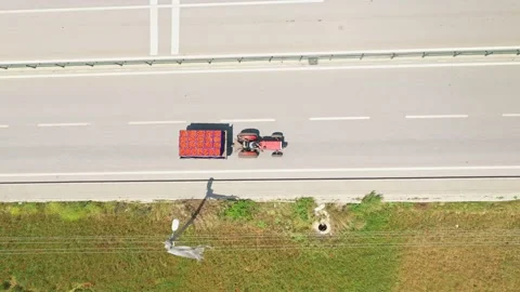 Red tractor carrying a full trailer driving on the road during harvest season Vídeo Stock 286356135