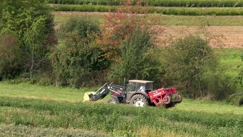 Red tractor driving over a pasture near farmland, agriculture, farming, rural Stock Footage 80273551