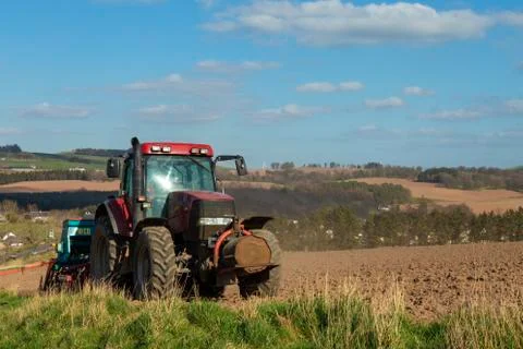 Red Tractor on a field in springtime. Stock Photos