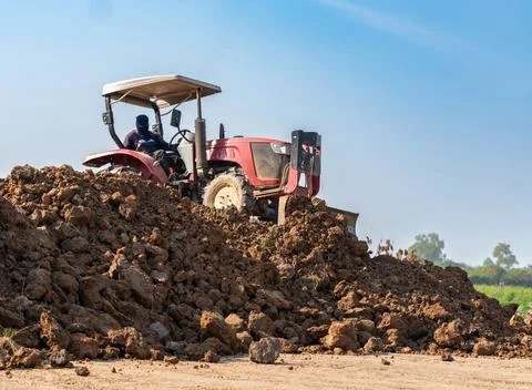 Red tractor with front blade leveling soil on a construction site Stock Photos