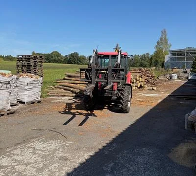 Red tractor with front loader at a sawmill. Stock Photos