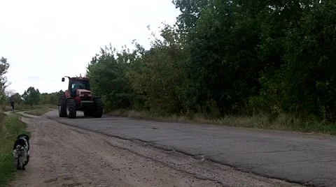 Red tractor goes on the road on the background of trees Stock Footage 50374163