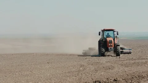 Red tractor with harrows prepares the dry field agricultural land. Stock Footage