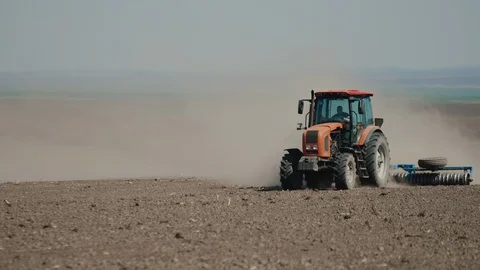 Red tractor with harrows prepares the dry field agricultural land. Video stock 128365174