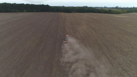 Red tractor on a hay field in front of green trees Stock Footage 167551375
