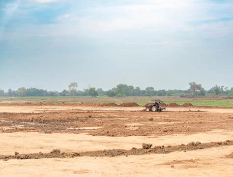 Red tractor leveling soil on a large open land development project. Foto stock