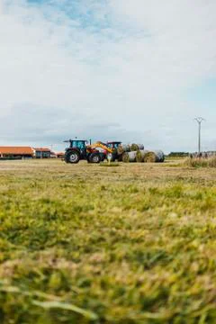 Red tractor loading a trailer with straw bales Stock Photos