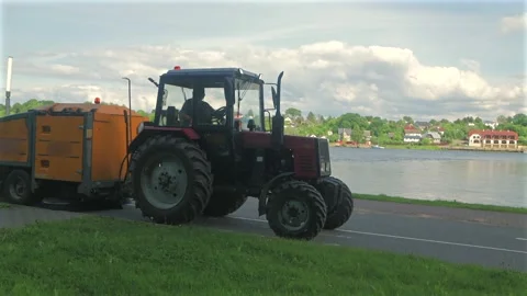 Red Tractor with Orange Street Sweeper Driving in Slow Motion Along  Road Stock Footage 337880130