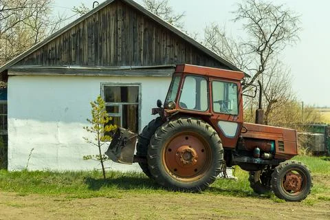 A red tractor parked outside a white farmhouse Stock Photos