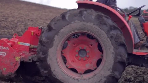 Red tractor plowing the earth Видео 75166866