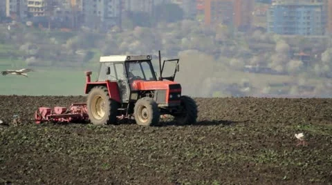 Red tractor plowing a field Stock Footage 22037597