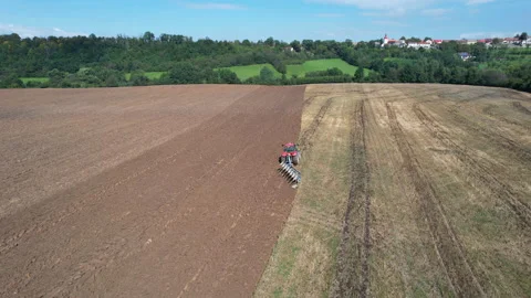 Red Tractor plowing a large field. Farmer on a tractor preparing the land for Stock Footage 161851079