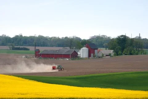 Red tractor plowing in spring Stock Photos