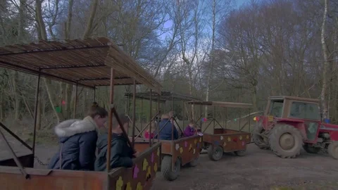 Red tractor pulling train of children in carts Stockbeeldmateriaal 84650684