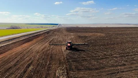 The red tractor works in the field in the spring Stock Photos