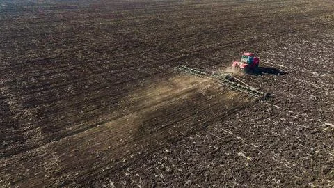 The red tractor works in the field in the spring Photos