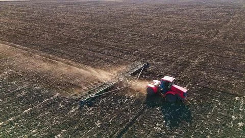 The red tractor works in the field in the spring Stock Photos