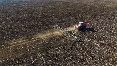 The red tractor works in the field in the spring Stock Photos