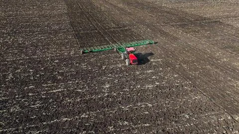 The red tractor works in the field in the spring Stock Photos
